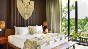 A modern bedroom with a large bed, wooden headboard, and a view of greenery outside. - Luxury Studio near Tulum beach, fast WI-FI and AC! (Tulum)
