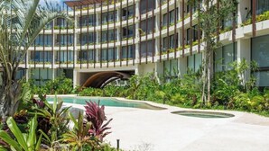 A modern hotel with multiple balconies, a swimming pool, and lush landscaping. - Luxury Studio near Tulum beach, fast WI-FI and AC! (Tulum)