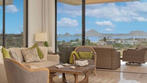 A spacious living area with a large window offering a view of the sea and mountains. There is a sofa, a chair, and a small table with decorative items. - Ocean view, fast Wi-Fi, shared pool and BBQ (Cabo San Lucas)
