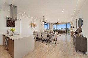 A spacious living area with a dining table, sofas, and a view of the outdoors. - Ocean view, fast Wi-Fi, shared pool and BBQ (Cabo San Lucas)