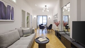 Ein modernes Wohnzimmer mit einem grauen Sofa, einem runden Couchtisch und einem Essbereich mit Tisch und Stühlen.