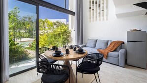 Ein zeitgemäßer Wohnraum mit Essbereich, einem grauen Sofa und einem Kühlschrank.
