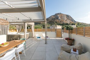 Terraço no telhado com área de jantar, espreguiçadeiras e vista para uma montanha.