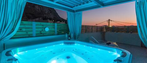 A hot tub with a view of a sunset and a wooden deck.