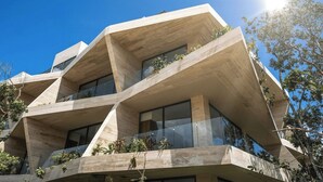 Un bâtiment moderne au design angulaire original, doté de nombreux balcons ornés de plantes et de grandes fenêtres.