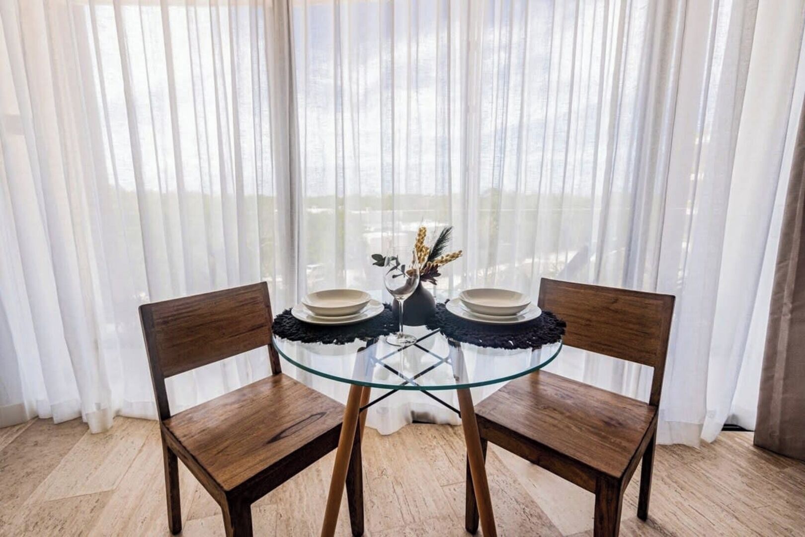 A dining table with two chairs, a glass top, and a decorative centerpiece.