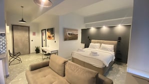 Ett modernt hotellrum med en säng, ett skrivbord, en stol och en soffa.