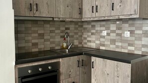 A kitchen with wooden cabinets, a black countertop, a tiled backsplash, and a built-in oven. - Monastiraki 101 @SuperHost Hub (Athina)
