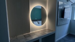 A modern room with a built-in circular mirror, a bed with a headboard, and a TV mounted on the wall. - Monastiraki 101 @SuperHost Hub (Athina)