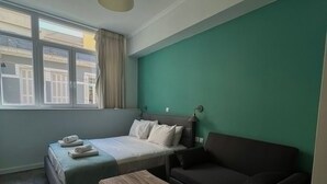 A modern room with a bed, a sofa, a wooden coffee table, and a window with curtains. - Monastiraki 101 @SuperHost Hub (Athina)