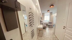Een moderne hotelkamer met een grote spiegel, een bank, een klein tafeltje en een stoel.