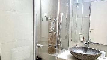 A modern bathroom with a glass-enclosed shower, a large mirror, and a vessel sink.