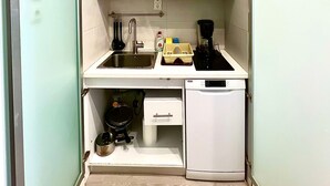 A compact kitchen with white cabinets, a sink, a coffee maker, and a dishwasher. - Monastiraki 106 @SuperHost Hub (Athina)