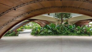 Un ambiente interno con soffitto in legno curvo e un'area giardino centrale.