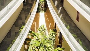 Atrio a più livelli con ringhiere in vetro, un giardino centrale e pavimento piastrellato.