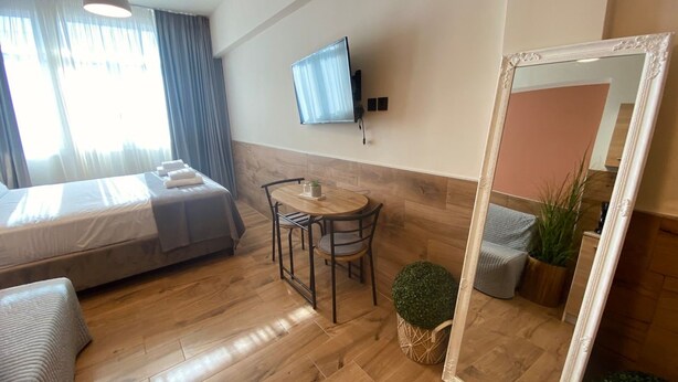 Une chambre d’hôtel avec un lit, une petite table ronde avec des chaises, un téléviseur fixé au mur et un grand miroir.