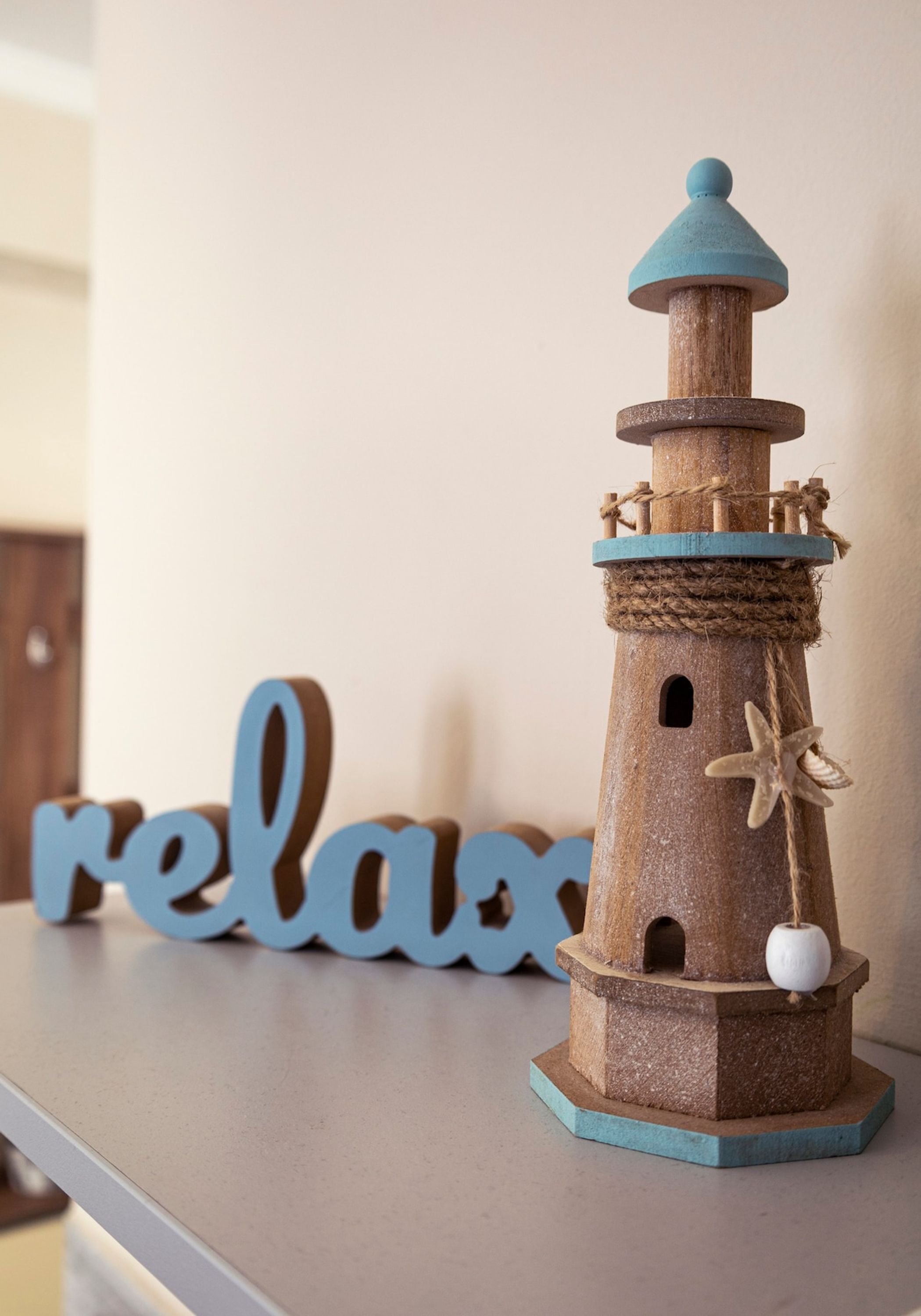Ein hölzernes Leuchtturm-Modell mit Krawilletails und einer Meerstern-Dekoration auf einem Regal.