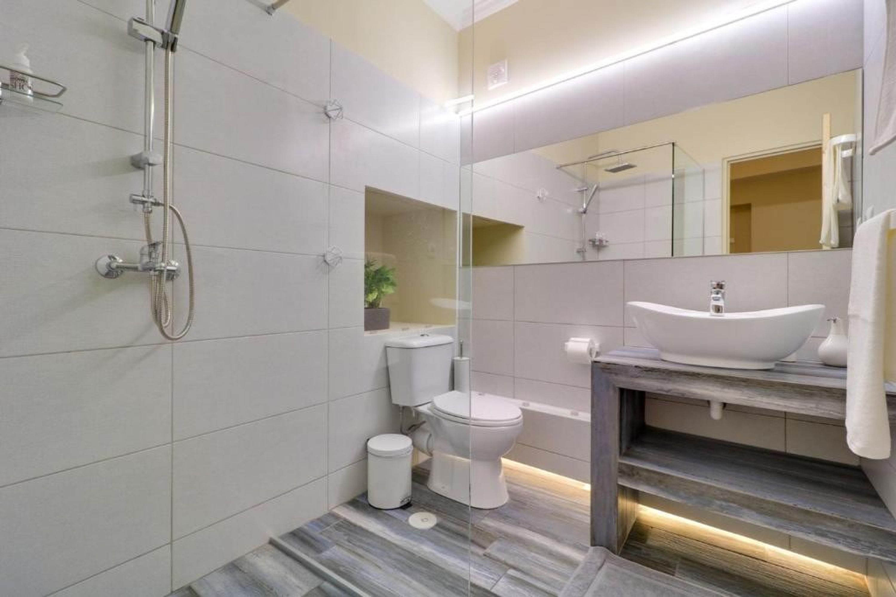 Ein modernes Badezimmer mit Glasdusche, weißer Toilette und Waschtisch mit Spüle und Spiegel.