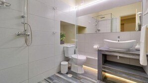 Een moderne badkamer met een douchecabine van glas, een wit toilet en een wastafel met een wastafel en spiegel.