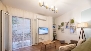 Una sala de estar con suelo de madera, televisor, sofá, mesa y lámpara.