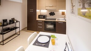 Una cucina compatta con forno a microonde, forno e un piccolo angolo ristoro con tavolo apparecchiato per due.