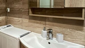 Un baño moderno con lavamanos integrado, un espejo y un perchero para toallas.