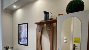 Una habitación con un aparador de madera, una mesa de vidrio con plantas, un cuadro enmarco y un espejo con un letrero.