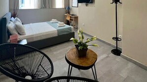 Una habitación de hotel moderna con cama, escritorio, televisor, una planta y dos sillas.