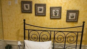 A bed with a white quilt, a pillow, and a folded towel on a headboard. There are three framed pictures on the wall above the bed. - VanDusen Homestay in Vancouver Close to UBC and Public Transits (Vancouver)
