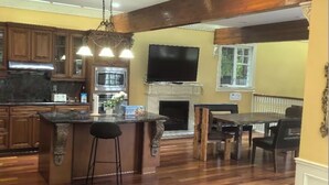 A spacious kitchen with wooden flooring, a central island, and a ceiling fan. - VanDusen Homestay in Vancouver Close to UBC and Public Transits (Vancouver)