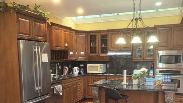 A modern kitchen with wooden cabinets, stainless steel appliances, and a herringbone wood floor. - VanDusen Homestay in Vancouver Close to UBC and Public Transits (Vancouver)