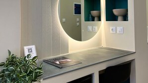Ein modernes Badezimmer mit einem runden Spiegel, einem Waschbecken und einem Ablagebereich mit dekorativen Schalen.