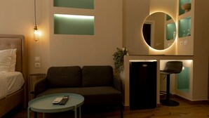 Ein modernes Hotelzimmer mit Bett, Sofa, kleinem Tisch und einer Küchenzeile.