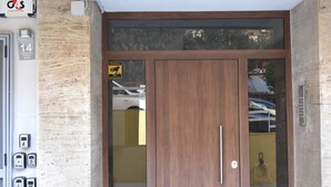 A building entrance with a wooden door, a glass panel, and a numbered doorbell. - Athens Ianos B by Super Host Hub (Μενεμένη)