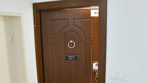 A brown door with a nameplate reading "IANOS IRIS" and a fire extinguisher mounted on the wall to the right. - Athens Ianos B by Super Host Hub (Μενεμένη)