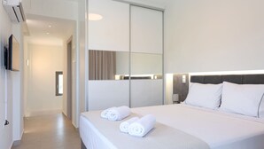 Une chambre d’hôtel moderne dotée d’un grand lit, d’un téléviseur à écran plat fixé au mur et d’un placard à portes coulissantes.