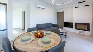 Un salon moderne avec une table à manger ronde en bois, des canapés gris et une cheminée.