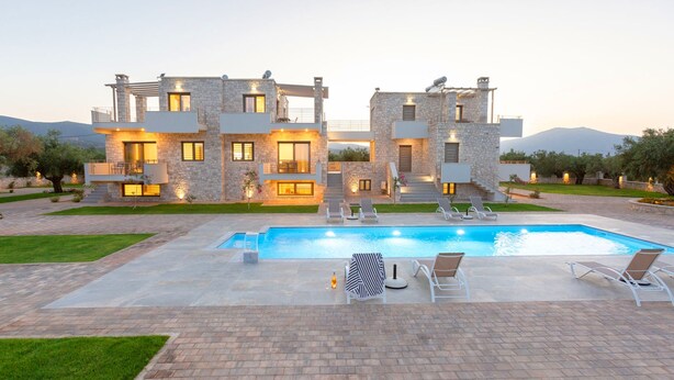 Une maison moderne à deux étages, dotée d’une piscine, d’un espace de détente extérieur et d’un jardin bien entretenu.