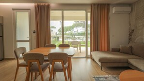 Una sala de estar moderna con comedor, sofá y puerta corrediza de vidrio que da a un jardín.