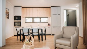 Una cucina moderna con mobili in legno, un tavolo da pranzo con sedie, un frigorifero e una finestra.
