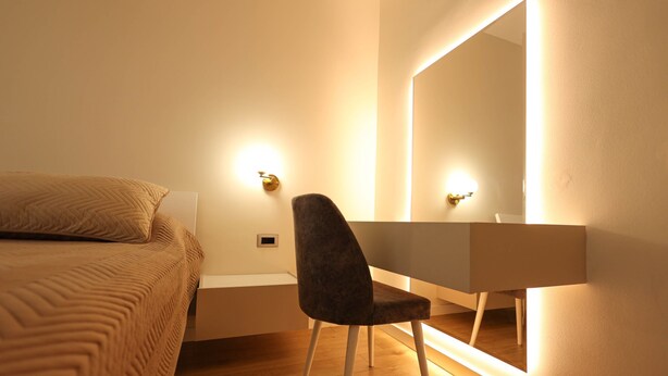A bedroom with a bed, a desk, and a large mirror. - Grandstay Portside in Durrës (Durrës)