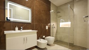 A modern bathroom with a large mirror, a bidet, a toilet, and a glass-enclosed shower. - Grandstay Portside in Durrës (Durrës)