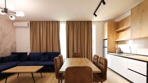 Een moderne woonruimte met een bank, eettafel, stoelen en een keukenhoek.