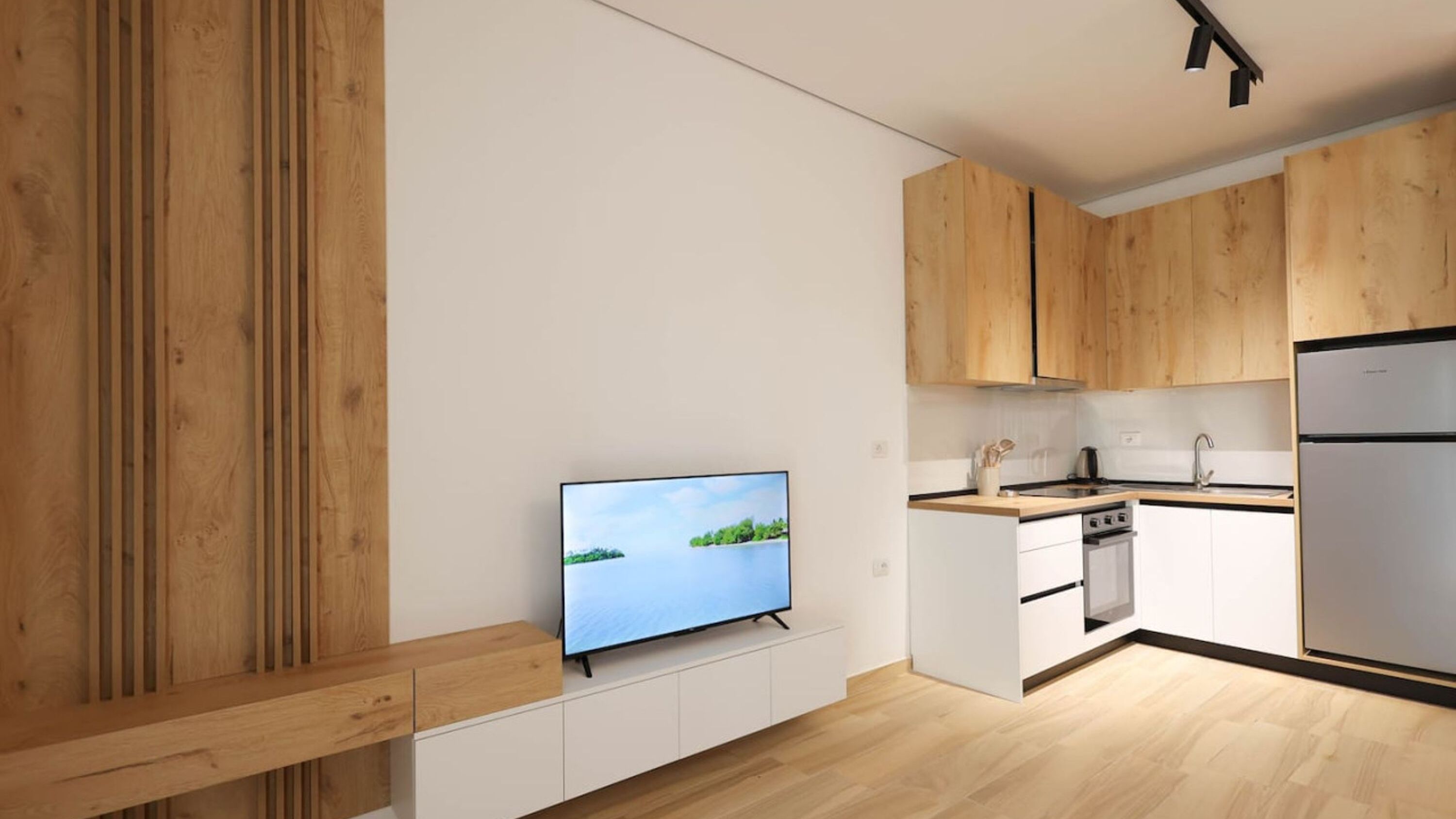 Une cuisine moderne avec des meubles en bois, un four encastré et un réfrigérateur en acier inoxydable.