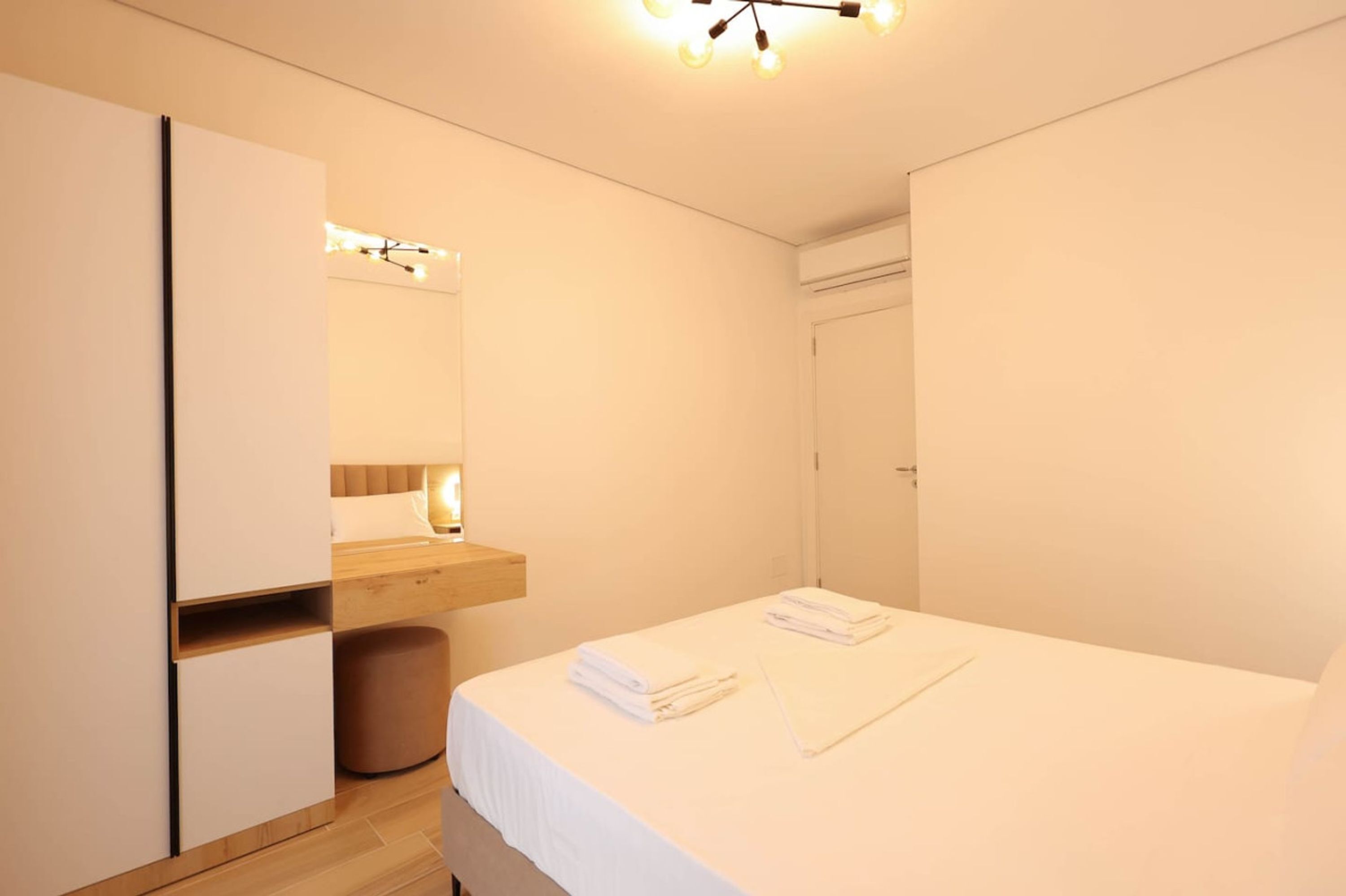 Ein modernes Hotelzimmer mit Bett, Nachttisch, Spiegel und Kleiderschrank.