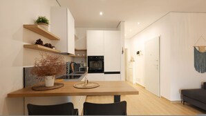 Een moderne keuken met witte kastjes, een houten eettafel en een zwarte oven.