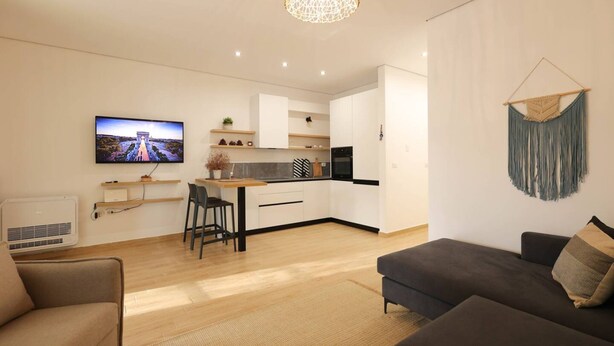 Een moderne woonkamer met een bank en een televisie waarop een mooi landschap te zien is.