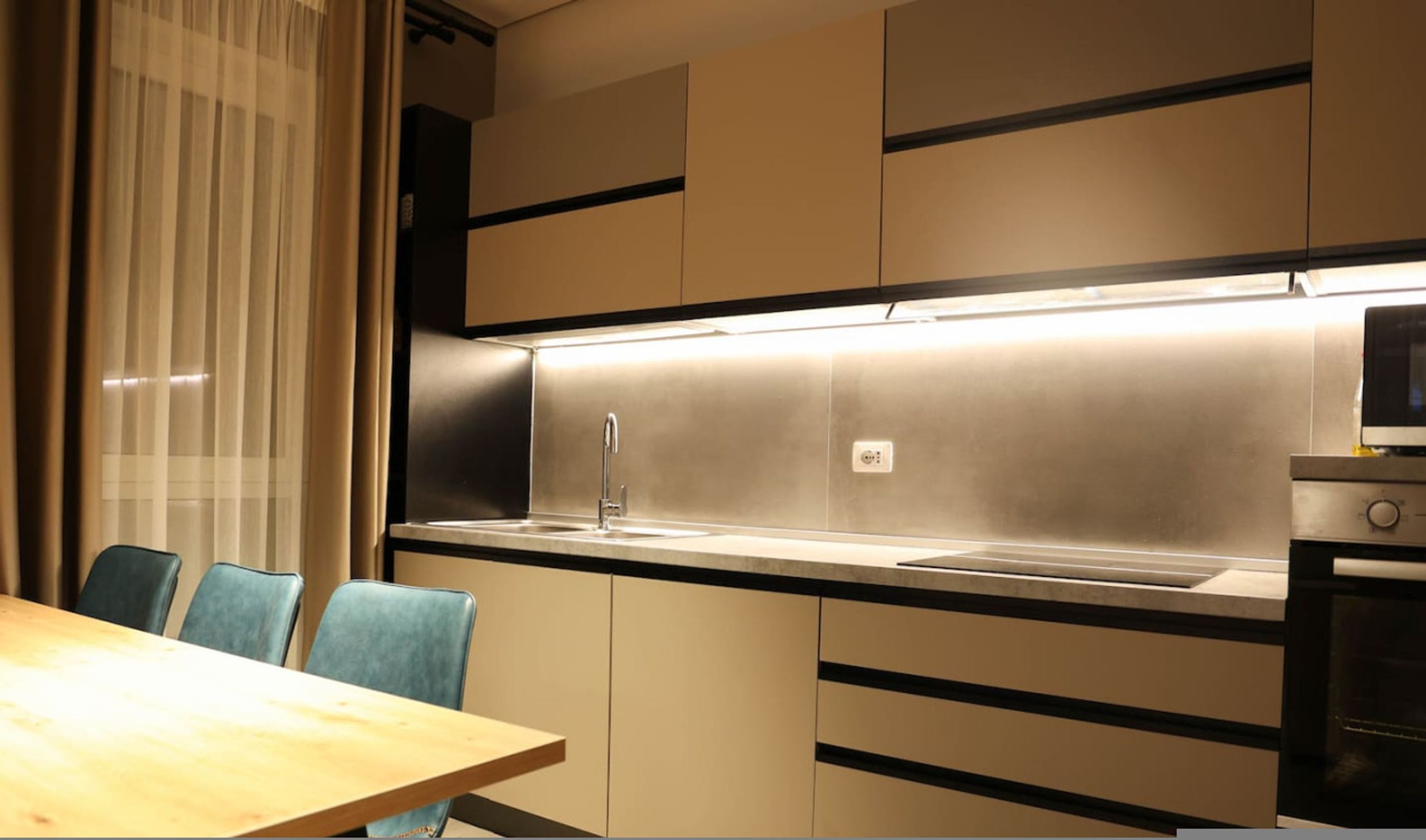 Una cucina moderna con lavello in acciaio inossidabile, forno a microonde e zona pranzo con tavolo e sedie.