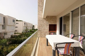 A balcony with a table and chairs, a stone wall, and a view of neighboring buildings. - SanPietro Vacation Apartment 020 (Plazhi San Pietro)