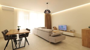 Ein modernes Wohnzimmer mit einer Couch, einem Esstisch, Stühlen und einem Fernseher.